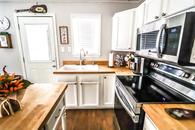 kitchen featuring a sink, stainless steel appliances, butcher block countertops, and white cabinets