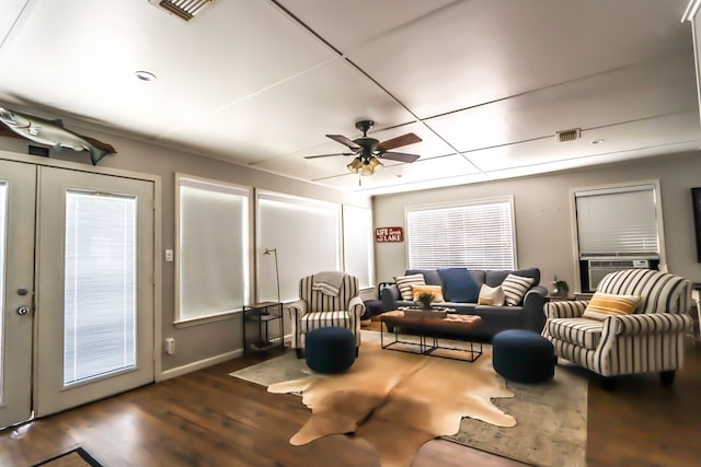 living area with cooling unit, visible vents, wood finished floors, and a ceiling fan