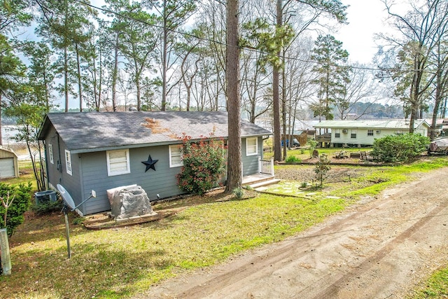 single story home featuring an outbuilding, a garage, cooling unit, and a front yard