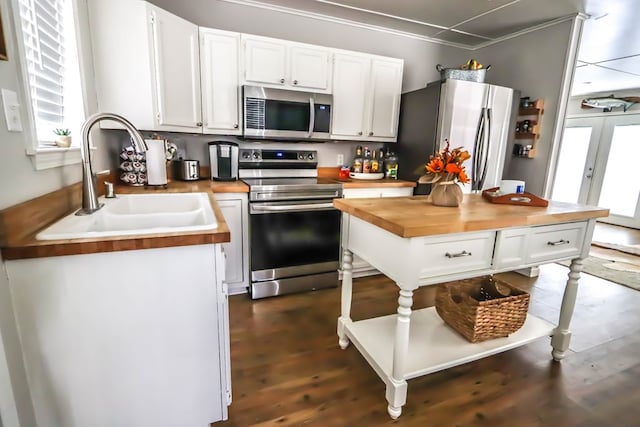 kitchen featuring wooden counters, white cabinets, appliances with stainless steel finishes, and a sink