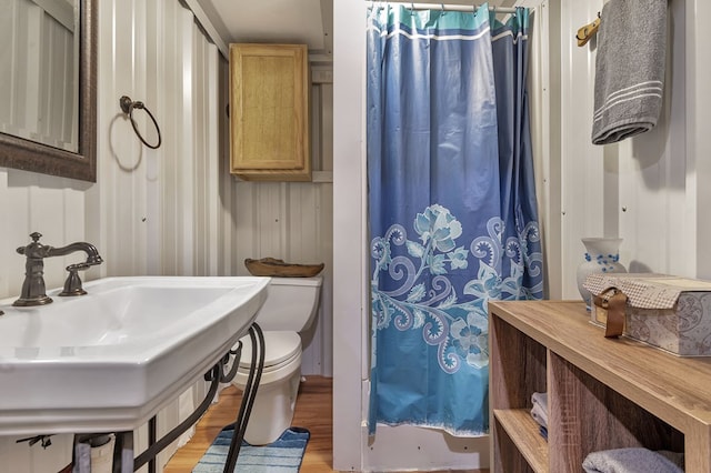 bathroom featuring hardwood / wood-style flooring, walk in shower, toilet, and sink