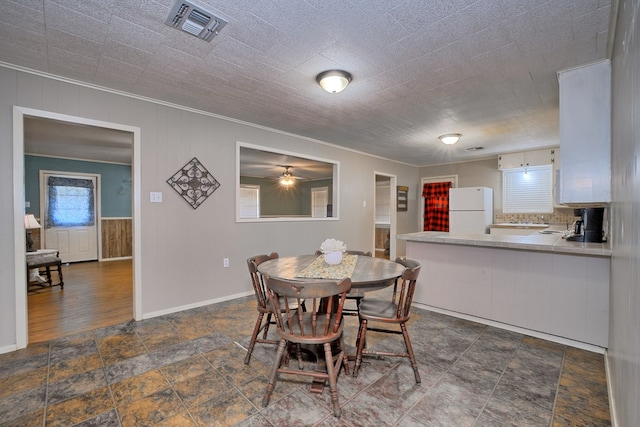 dining area with visible vents, stone finish floor, baseboards, and ornamental molding