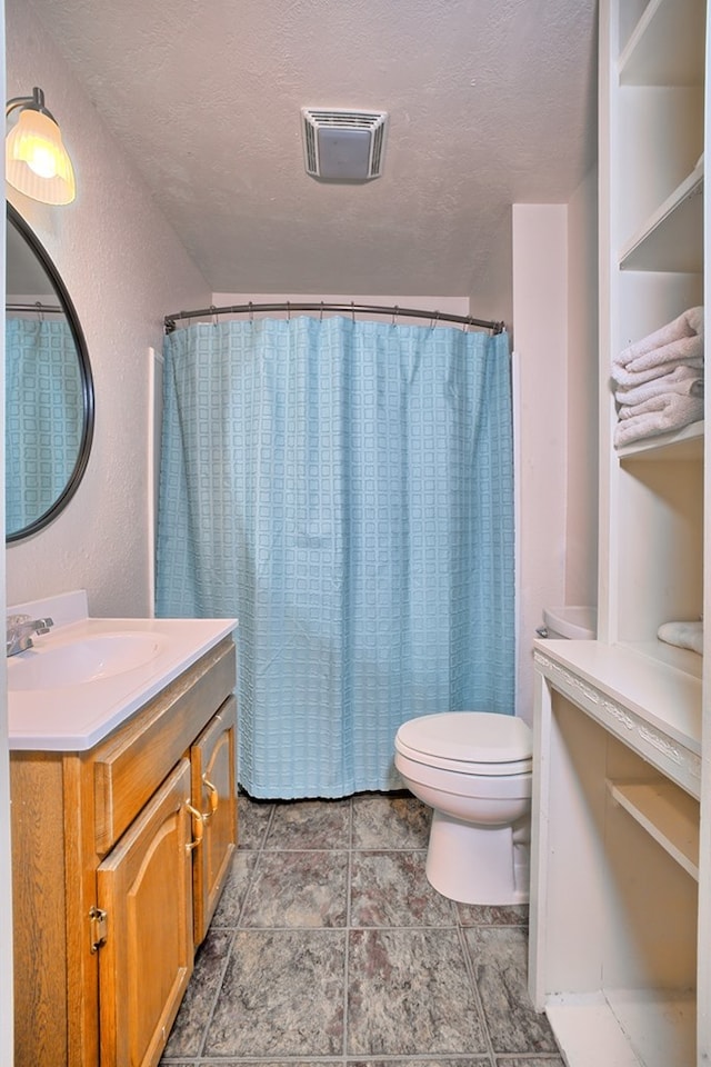 bathroom featuring visible vents, toilet, a textured ceiling, vanity, and a textured wall
