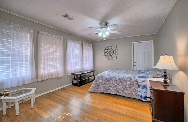 bedroom with visible vents, multiple windows, wood finished floors, and crown molding