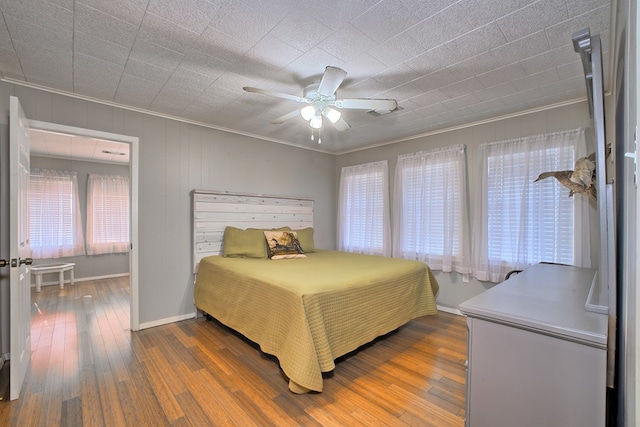 bedroom with a ceiling fan, hardwood / wood-style floors, and crown molding