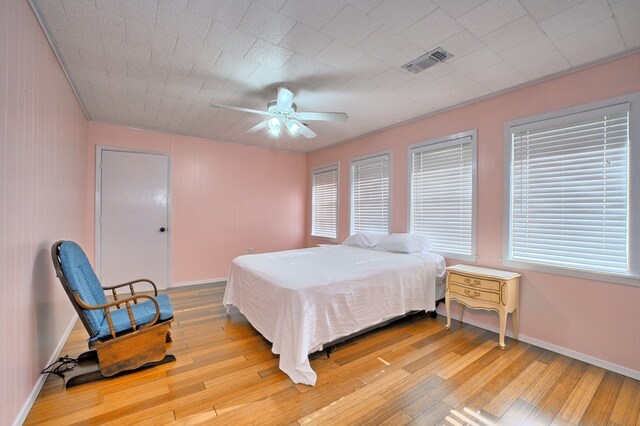 bedroom with wood finished floors, visible vents, and baseboards