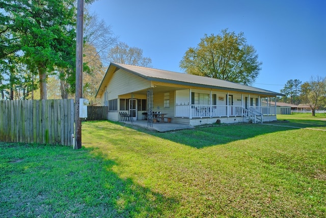rear view of house with metal roof, a lawn, a patio area, and fence