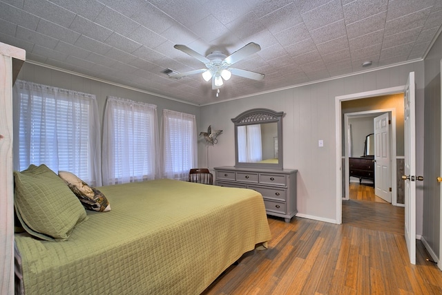 bedroom with visible vents, a ceiling fan, dark wood finished floors, crown molding, and baseboards