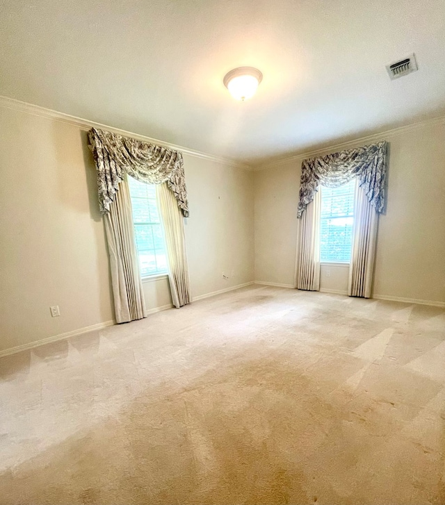 unfurnished room with ornamental molding, a wealth of natural light, and light colored carpet