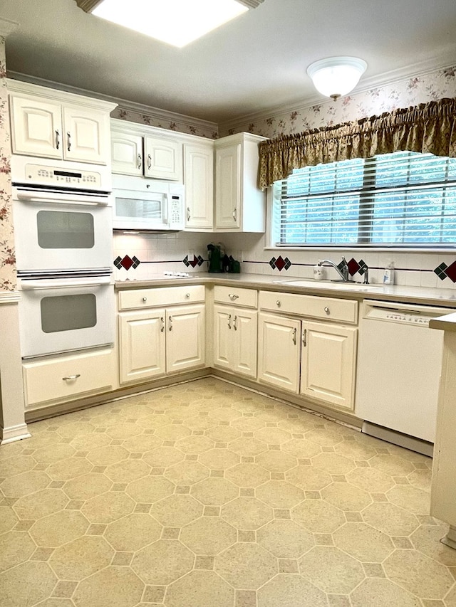 kitchen featuring white appliances, ornamental molding, and white cabinets