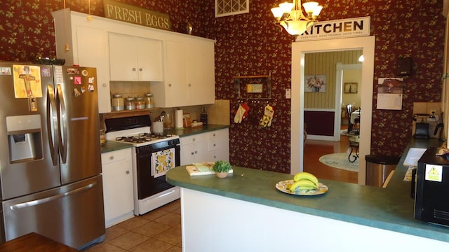 110 Market St, Hemphill, TX 75948 - kitchen featuring range with gas stovetop, wallpapered walls, visible vents, and stainless steel fridge with ice dispenser