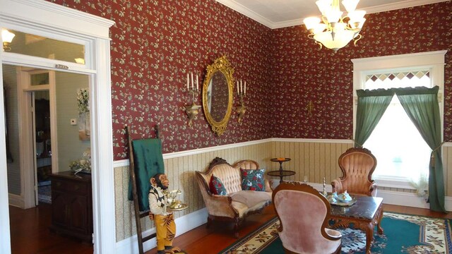 110 Market St, Hemphill, TX 75948 - sitting room with a chandelier, wood finished floors, wainscoting, and wallpapered walls