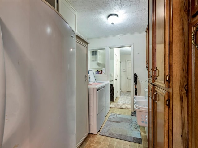 washroom with washer and dryer, a textured ceiling, and ornamental molding