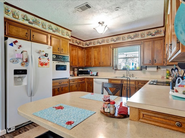 kitchen featuring kitchen peninsula, a textured ceiling, white appliances, and sink