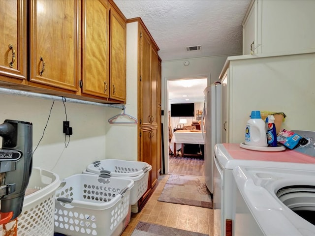 laundry room with washer and clothes dryer, cabinets, and a textured ceiling