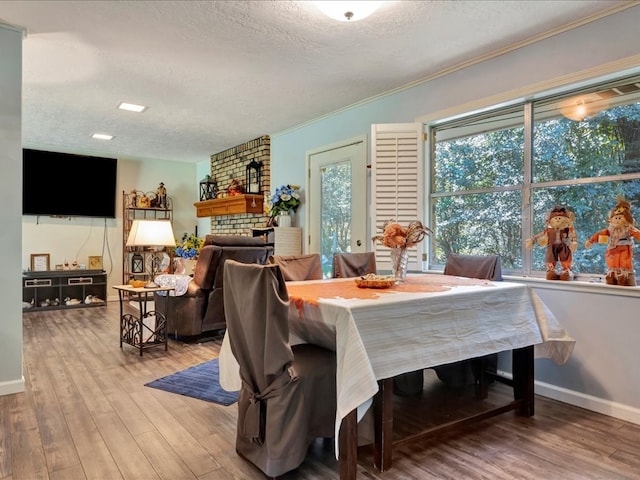 dining area with hardwood / wood-style floors, a fireplace, ornamental molding, and a textured ceiling