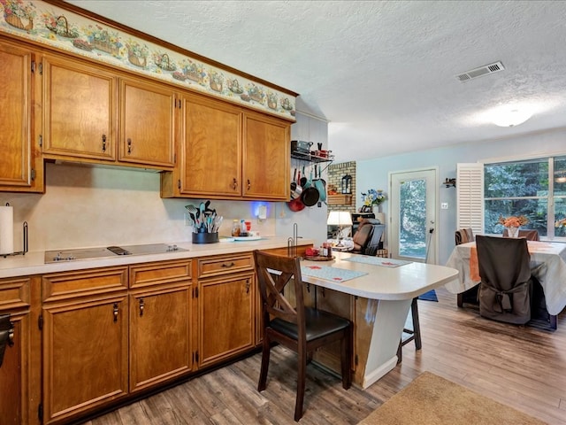 kitchen featuring white cooktop, light hardwood / wood-style floors, and a textured ceiling