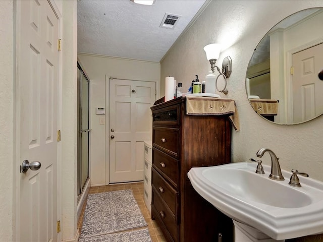 bathroom with tile patterned floors, sink, a textured ceiling, and walk in shower