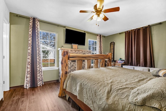 bedroom featuring multiple windows, wood finished floors, a ceiling fan, and baseboards