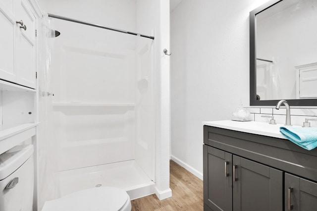 full bathroom with toilet, a stall shower, vanity, wood finished floors, and baseboards