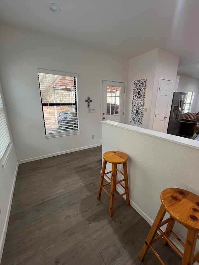 kitchen with plenty of natural light, dark hardwood / wood-style floors, kitchen peninsula, and a breakfast bar area