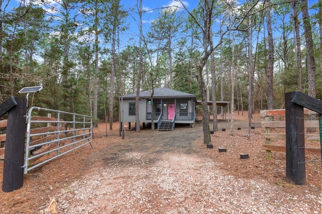 view of front of house with driveway, a gate, and roof with shingles