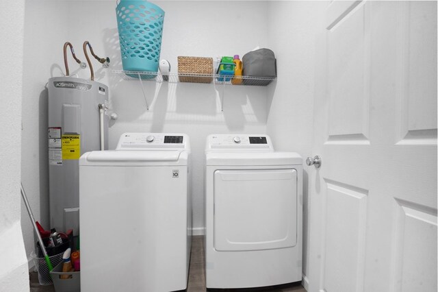 washroom with water heater, laundry area, and washing machine and clothes dryer