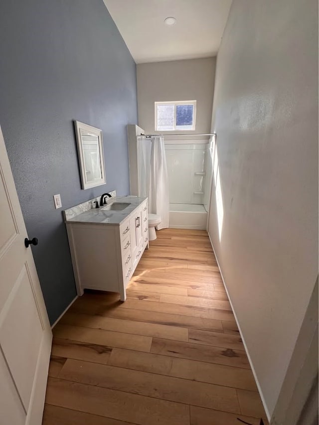 bathroom with baseboards, toilet, wood-type flooring, shower / tub combo with curtain, and vanity