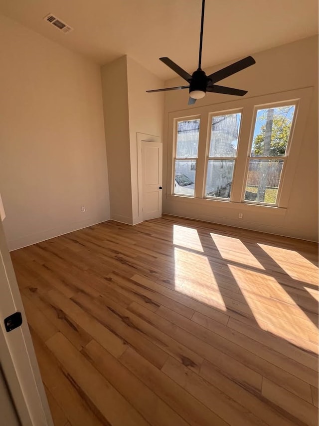 spare room featuring a ceiling fan, visible vents, and wood finished floors