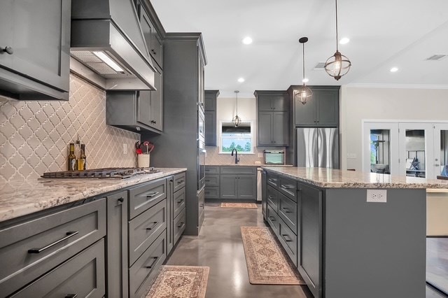 685 Box Car Rd, Lufkin, TX 75904 - kitchen with appliances with stainless steel finishes, wall chimney exhaust hood, gray cabinetry, a kitchen island, and tasteful backsplash