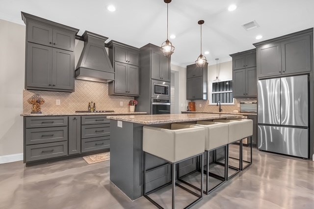 685 Box Car Rd, Lufkin, TX 75904 - kitchen featuring stainless steel appliances, custom range hood, decorative backsplash, finished concrete floors, and light stone countertops