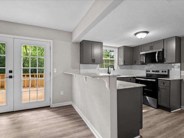 3202 Chimney Rock Ln, Nacogdoches, TX 75965 - kitchen featuring appliances with stainless steel finishes, gray cabinetry, a peninsula, light wood finished floors, and light stone counters
