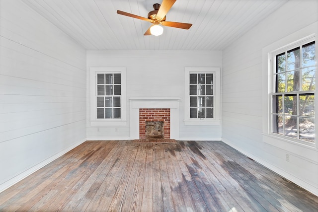 unfurnished living room with ceiling fan, wooden walls, wooden ceiling, and wood-type flooring