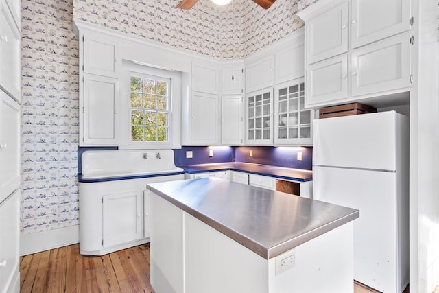 kitchen featuring white refrigerator, a center island, white cabinetry, and light hardwood / wood-style flooring