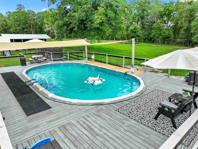 view of swimming pool featuring a wooden deck and a lawn