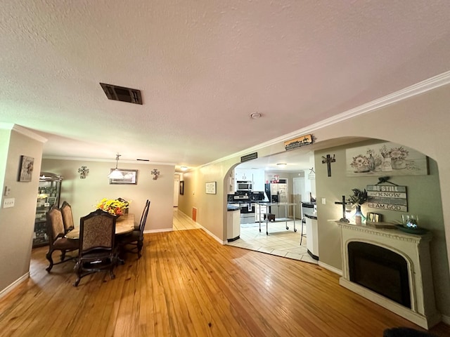785 County Road 105, San Augustine, TX 75972 - dining area featuring visible vents, arched walkways, light wood-style flooring, and ornamental molding