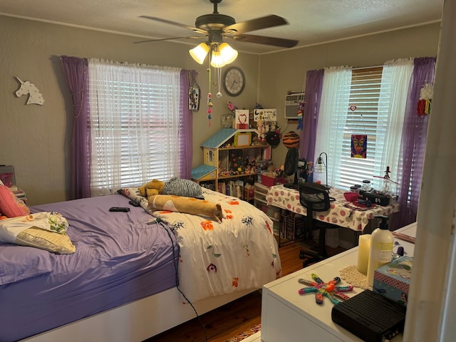 bedroom with a ceiling fan, a wall mounted air conditioner, multiple windows, and wood finished floors