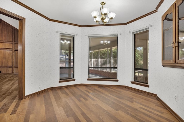 unfurnished room with hardwood / wood-style floors, ornamental molding, and a notable chandelier