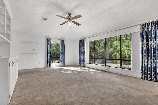 unfurnished living room featuring carpet flooring, plenty of natural light, ceiling fan, and a textured ceiling