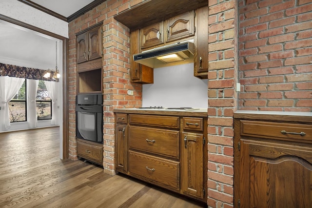 kitchen featuring light wood-type flooring, ornamental molding, white gas cooktop, a chandelier, and oven