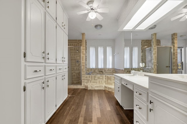 bathroom with hardwood / wood-style floors, ceiling fan, walk in shower, and vanity