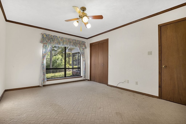 empty room featuring ceiling fan, crown molding, and light carpet