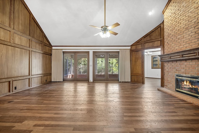 unfurnished living room with a fireplace, high vaulted ceiling, and wooden walls