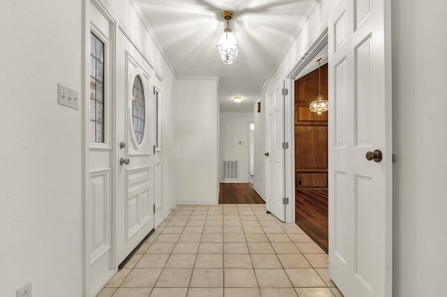 hall featuring a chandelier, light tile patterned floors, a textured ceiling, and crown molding