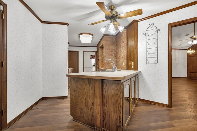 kitchen featuring kitchen peninsula, dark hardwood / wood-style floors, ornamental molding, and sink