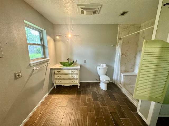 bathroom featuring vanity, a shower with curtain, hardwood / wood-style flooring, toilet, and a textured ceiling