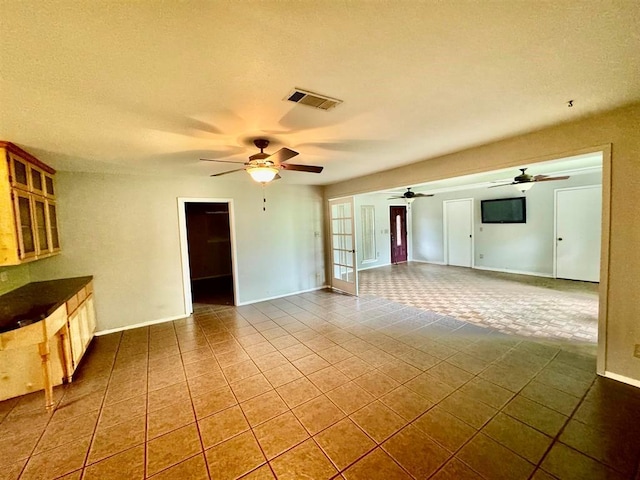 unfurnished living room featuring french doors, tile patterned floors, and ceiling fan