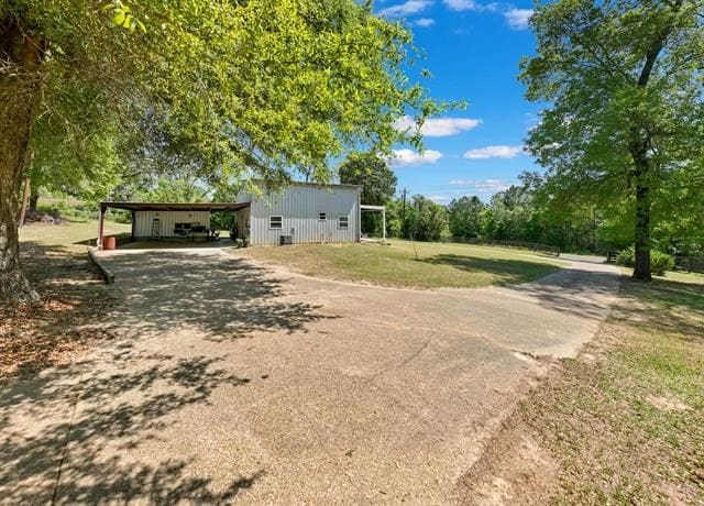 view of yard featuring dirt driveway and an outbuilding