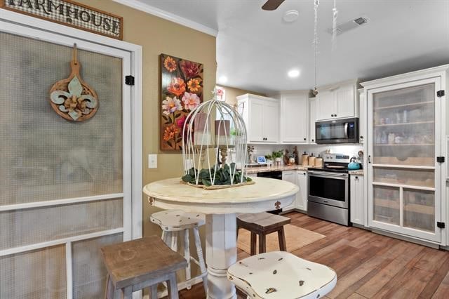 kitchen with light wood finished floors, white cabinets, visible vents, light countertops, and electric stove