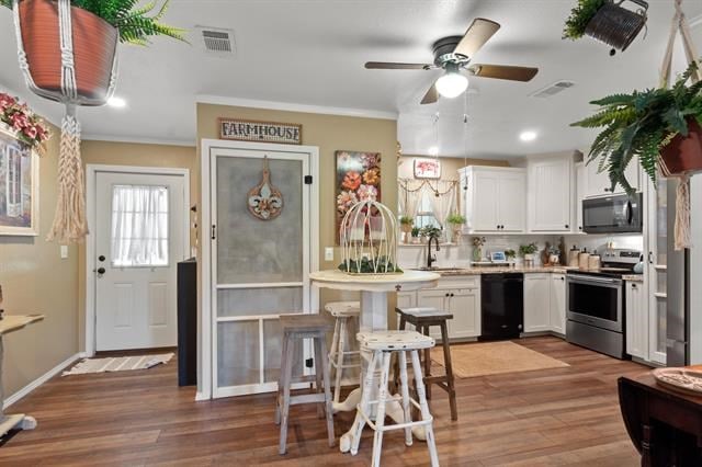 kitchen featuring light countertops, visible vents, a sink, black appliances, and white cabinetry